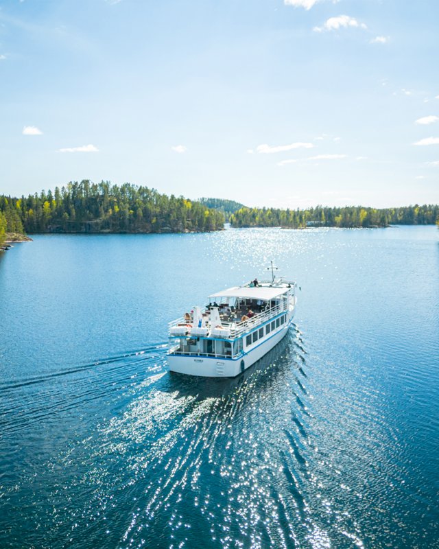 Valkoinen risteilyalus seilaa välkkyvässä vesistössä.